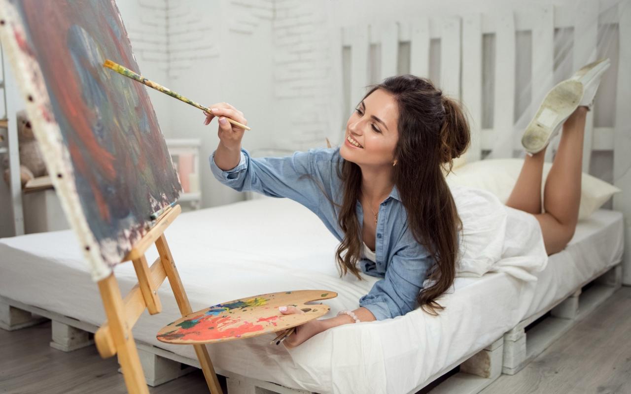 Голая длинноволосая художница рисует красками